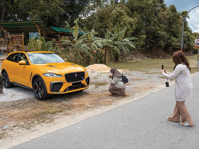 Members of the media photograph F-PACE SVR in Sorrento Yellow, which is parked at the side of a road.